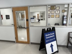 Image of Dr. Mark Brown's clinic exterior showing the building entrance with signage, clinic logo, and office hours displayed on the door.
