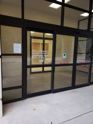 Image of Dr. Mark Brown's clinic exterior showing the building entrance with signage, clinic logo, and office hours displayed on the door.