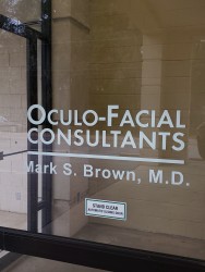 Image of Dr. Mark Brown's clinic exterior showing the building entrance with signage, clinic logo, and office hours displayed on the door.