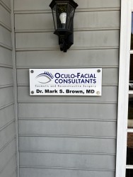 Image of Dr. Mark Brown's clinic exterior showing the building entrance with signage, clinic logo, and office hours displayed on the door.